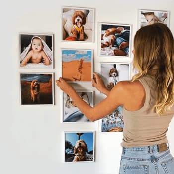 A young woman hangs photo tiles with images of her dog printed inside.